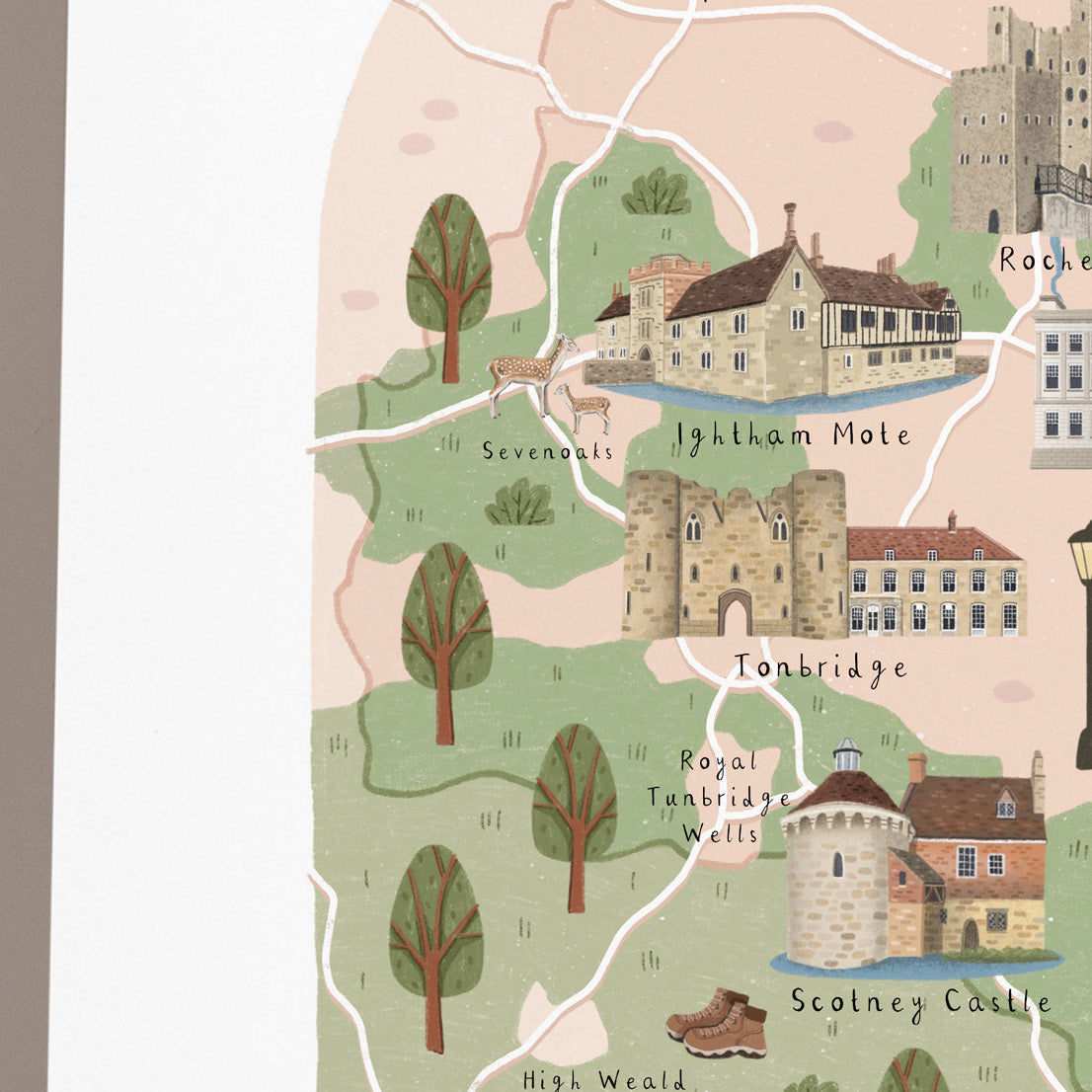 A close-up of a hand-drawn illustrated map print showing landmarks and buildings around Kent, including Tonbridge, Sevenoaks, Ightham Mole, Royal Tanbridge Wells, and Scotney Castle, with a light pink background and green landscape areas.