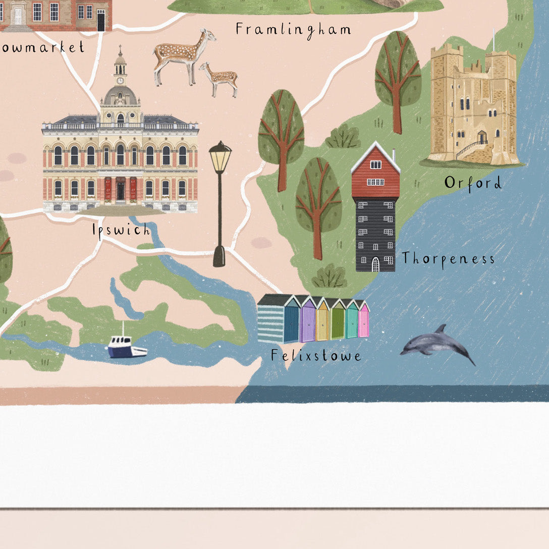 A stylized illustrated map print showing landmarks and places such as Framlingham, Ipswich, Orford, and Felxstowe, with trees, buildings, a boat, a dolphin, and beach huts on a pastel background.